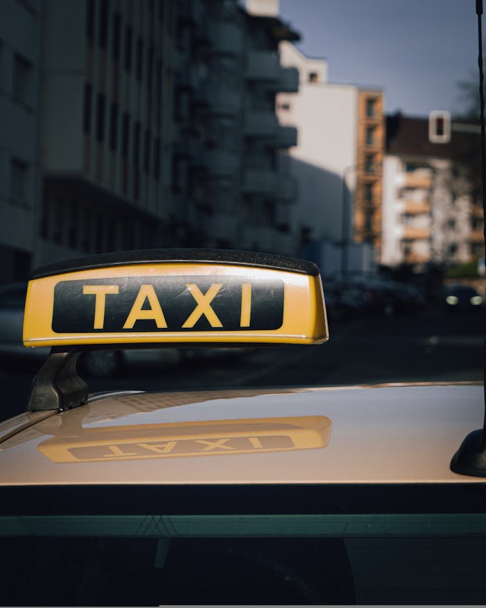 why-choose-us Close-up of a taxi sign on a car roof with an urban city background.