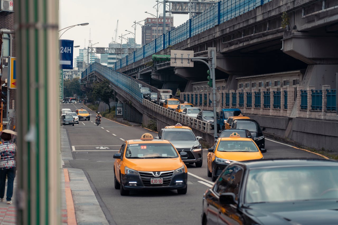gallery-1 Yellow taxis and vehicles navigating an urban street under an overpass.