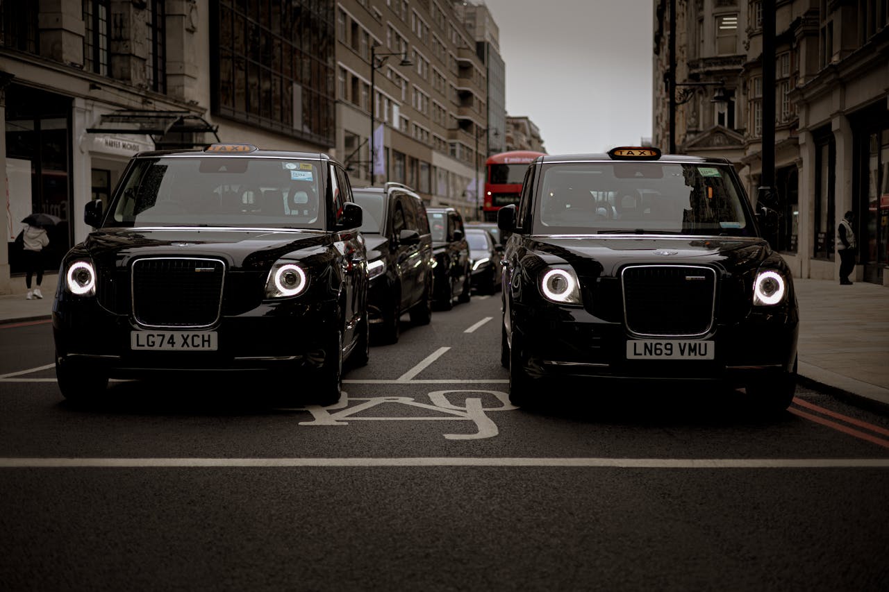gallery-4 Black taxis line up on a London street showcasing modern urban transportation.