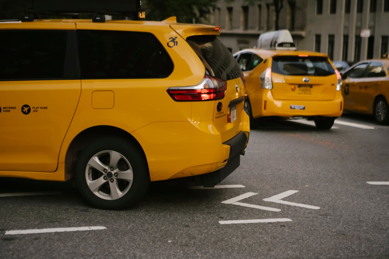 services-01 Modern yellow crossover taxi cars riding on asphalt road near commercial buildings in city