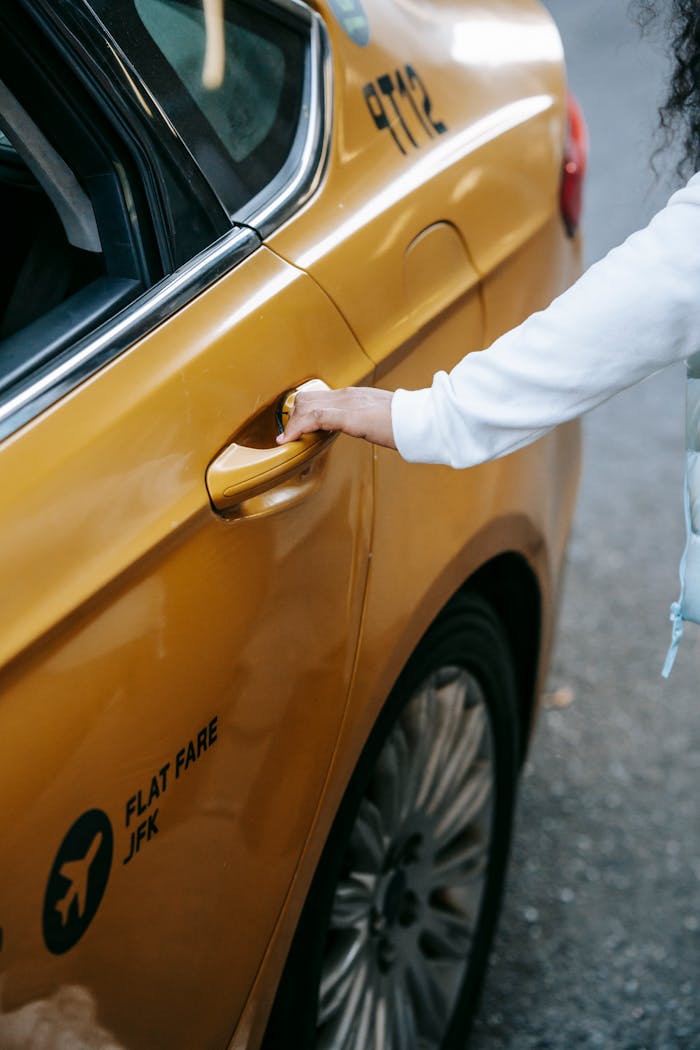 gallery-5 Crop unrecognizable ethnic lady in casual outfit opening door of yellow taxi in city street in daylight